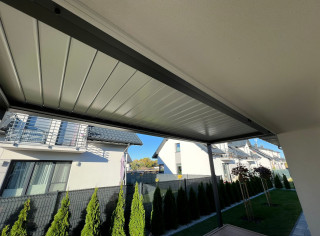 Pergola lamelowa model Sun Breaker montowana do ściany budynku. Dodatkowo oświetlenie LED