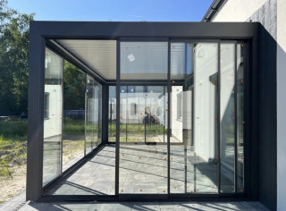 Louvered roof pergola enclosed by glass sliding walls