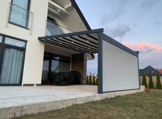 Pergola materiałową model Premium, kolor 7016ST, wersja przyścienna z oświetleniem LED, roletą boczną ZIP i tkaniną typu screen. Sterowanie na pilota firmy Somfy