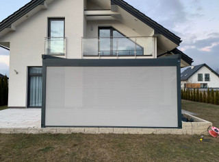 Pergola materiałową model Premium, kolor 7016ST, wersja przyścienna z oświetleniem LED, roletą boczną ZIP i tkaniną typu screen. Sterowanie na pilota firmy Somfy